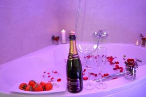 een fles champagne en een bord aardbeien op een bad bij Les Chambres d'Elza in Mouscron
