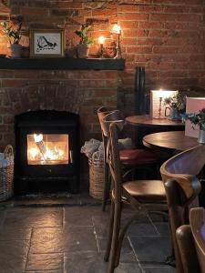 a fireplace in a restaurant with tables and chairs at The Plume of Feathers in Farnham