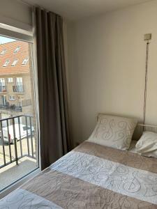 a bedroom with a bed and a large window at Ruim zonnig appartement op 50m van strand in Ostend
