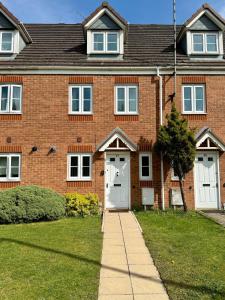 a red brick house with a white door at The Lakes in Stockingford