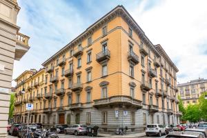 un grande edificio giallo con auto parcheggiate in un parcheggio di 5 minutes from Via Roma - with Smart TV a Torino
