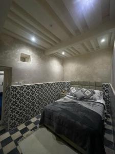 a bedroom with a bed and a checkered floor at Dar Lalla Rahma in Essaouira