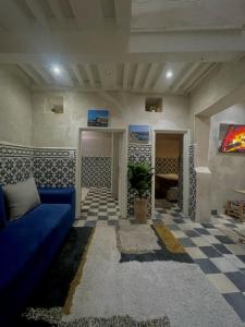 a living room with a blue couch and a checkered floor at Dar Lalla Rahma in Essaouira