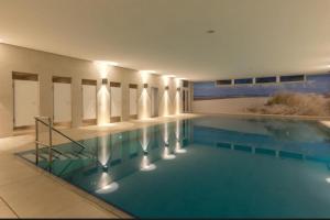 a swimming pool with blue water in a building at Atlantic 003- Exclusive Ferienwohnung mit Pool, Sauna und Fitnessbereich im Haus in Cuxhaven