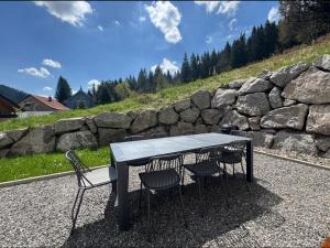 a table and chairs sitting next to a stone wall at "Chalet H28" mit 4 Schlafzimmer in Todtnau-Muggenbrunn in Muggenbrunn