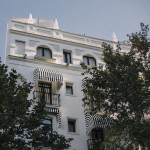 a white building with windows and a balcony at Petit Palace Puerta de Triana in Seville