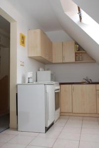a kitchen with a white refrigerator and wooden cabinets at Iso Apartman Siófok in Siófok