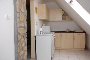 a small kitchen with a white refrigerator in a attic at Iso Apartman Siófok in Siófok