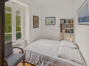 a bedroom with a bed and a chair and a book shelf at Maison à 30m de la plage - Grand Jardin - pour 6 in Île-Tudy