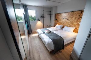 a bedroom with a large white bed and a window at The Originals Access, Hôtel Clermont-Ferrand Nord in Châteaugay