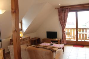 a living room with a couch and a television at Maison d'Hôtes Sainte Hune Chambres et appartements in Hunawihr