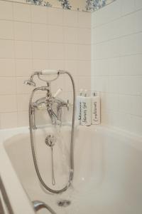 a bath tub with a shower in a bathroom at Claggan Farmhouse, Loch Tay in Aberfeldy