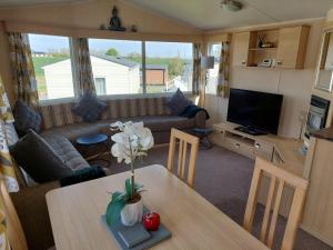 a living room with a table and a couch at Lotus Lodge Northumberland in Felton