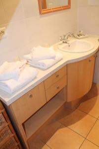 a bathroom with a sink and a mirror and towels at Maison d'Hôtes Sainte Hune Chambres et appartements in Hunawihr