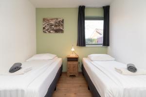 two twin beds in a room with a window at Les Maisons Domburg in Domburg