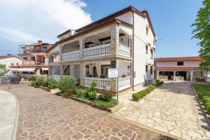 een wit gebouw met een balkon in een straat bij Apartments Frama Poreč - Funtana in Funtana