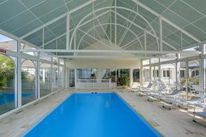 a large swimming pool in a building with chairs around it at LOGIS Hôtel ARCADIA in Lannion