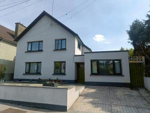 a white house with black windows and a driveway at Dingle Atlantic Lodge Accommodation in Dingle