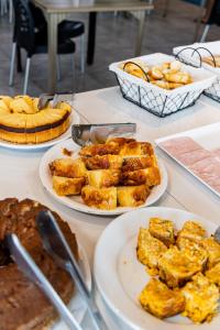 ein Tisch voller Teller mit Essen und Kuchen in der Unterkunft Rota 232 Hotel Caruaru in Caruaru