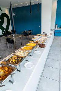 ein Buffet mit vielen Tabletts voller Speisen in der Unterkunft Rota 232 Hotel Caruaru in Caruaru