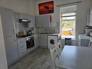a kitchen with white cabinets and a table and a dining room at The Tramway House in Carrickfergus