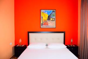 a bedroom with an orange wall and a white bed at VILA LILI Guest House - Berat in Berat