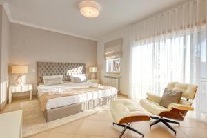 a bedroom with a large bed and two chairs at Praia D'el Rey - A4 in Óbidos