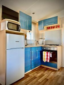 a kitchen with blue cabinets and a white refrigerator at Relax tra gli ulivi casetta GIADA in La Sdriscia