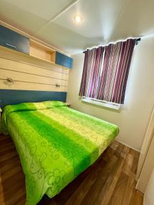 a green bed in a room with a window at Relax tra gli ulivi casetta GIADA in La Sdriscia