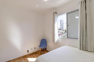 a bedroom with a blue chair and a window at Apto - Metrô Alto do Ipiranga in Sao Paulo