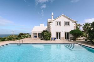 a house with a swimming pool in front of a house at OUTPOST - Casa das Arribas in Azenhas do Mar