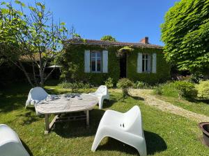 a garden with a table and chairs in front of a house at Cottage-Saint Laurent sur Sèvre in Saint-Laurent-sur-Sèvre