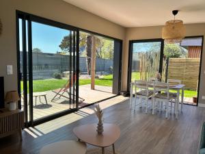 a living room with sliding glass doors and a table at Maison Bâbord, Près des plages et du centre GR34 WIFI in Trégastel