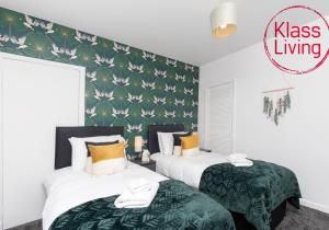 a bedroom with two beds with green and white sheets at Sanderson Upper by Klass Living Uddingston in Uddingston