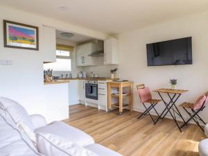 a living room with a couch and a kitchen at Hill View in Tywyn