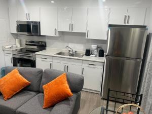 a kitchen with a gray couch with orange pillows at Peaceful Haven in Saskatoon