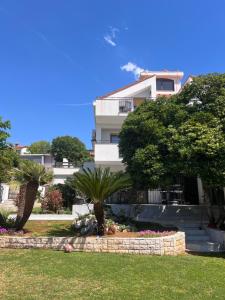 a white building with trees and flowers in a yard at Vila Peričić in Dramalj
