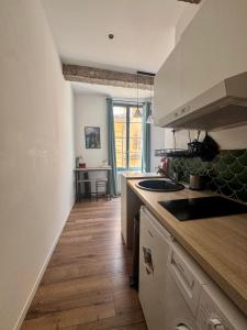 a kitchen with white cabinets and a wooden floor at Stud'Arles in Arles