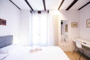 a white bedroom with a white bed and a desk at Tesoro Dé Galluzzi in Bologna