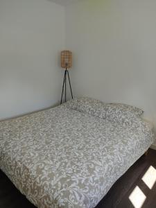 a bed with a white comforter in a bedroom at appartement indépendant f2 avec terrasse et jardin in Cannes-et-Clairan