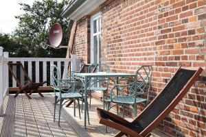 a table and chairs on a porch with a brick wall at Panorama-Loft Fehmarn mit Meerblick in Fehmarn