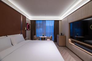 a hotel room with a large bed and a flat screen tv at 桔子水晶上海江桥万达酒店 in Shanghai