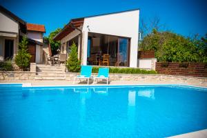 a swimming pool with two blue chairs next to a house at Villa Tia in Mostar
