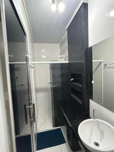 a bathroom with a glass shower and a sink at Casa da piscina in Macapá