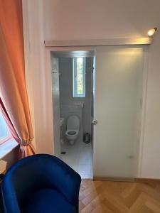a bathroom with a toilet and a window and a blue chair at Vila Doctor Popovici in Prăjila