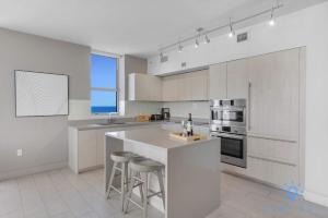Una cocina con gabinetes blancos y una encimera con taburetes. en High-Floor with Stunning Views-Luxury Condo - Pools, en Hollywood