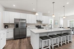 a kitchen with white cabinets and a large island with bar stools at Brand-New 6BR Home Near Ocean City Pools, Gym, Tennis & Bay Access in Berlin