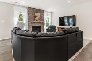 a black leather couch in a living room with a fireplace at Brand-New 6BR Home Near Ocean City Pools, Gym, Tennis & Bay Access in Berlin