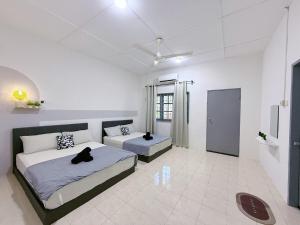 Dos camas en una habitación blanca con dos gatos negros sobre ellas. en Outdoor BBQ Air Putih 4R3B Homestay, en Kuantan 6 fotos más