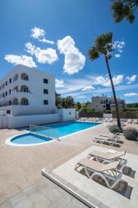 a swimming pool with lounge chairs and a building at Pierre & Vacances Ros Ibiza in Santa Eularia des Riu